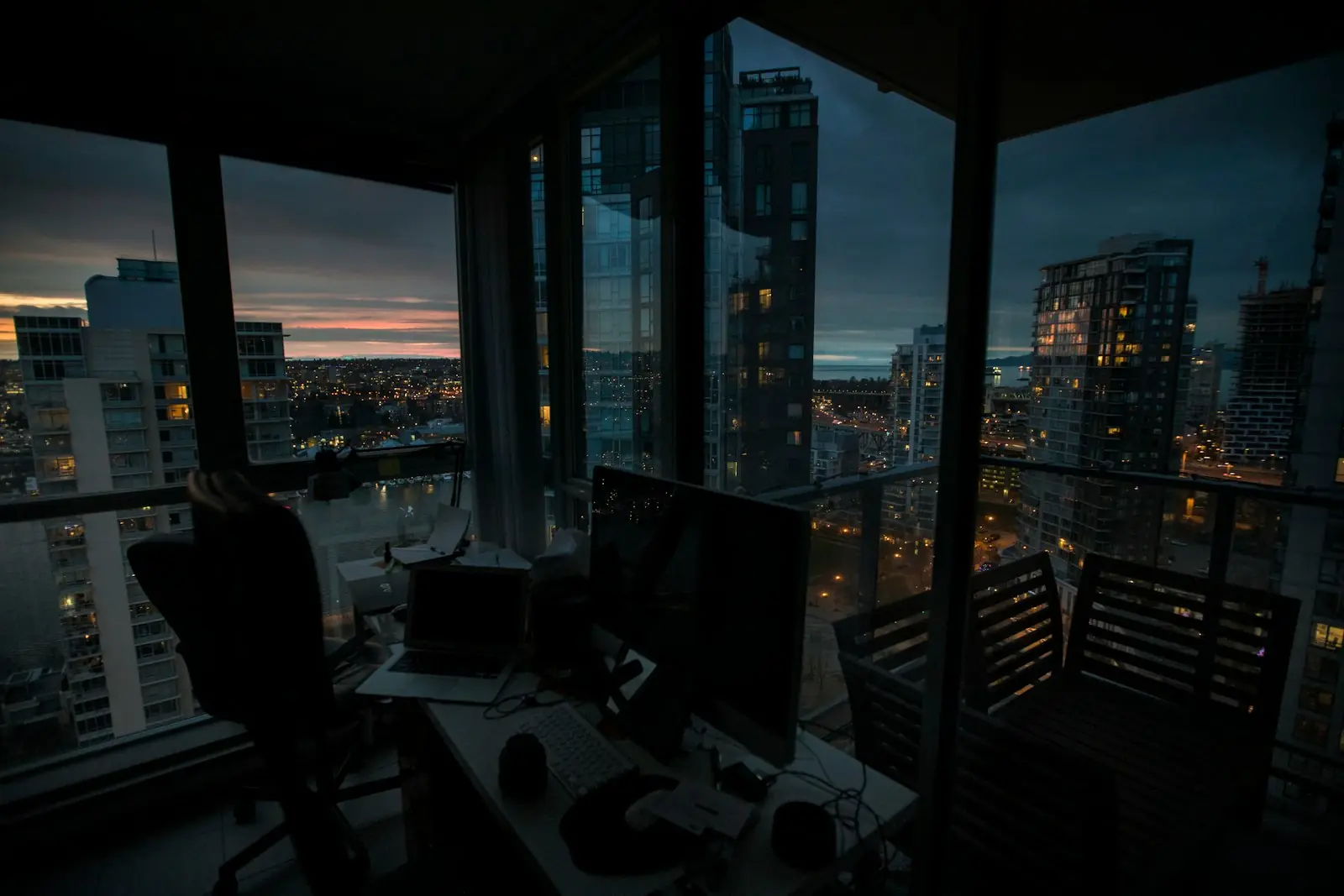 A workstation in a high-rise at dusk, city lights beyond the glass