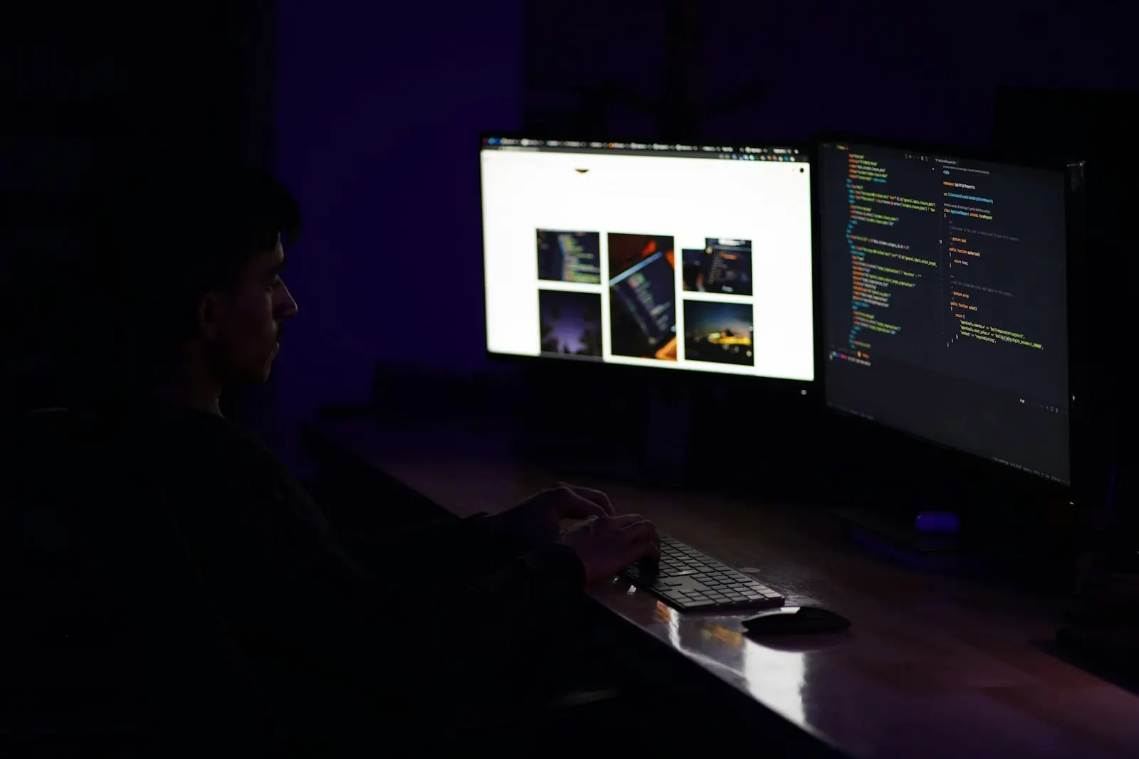 A developer at two monitors in a dark room